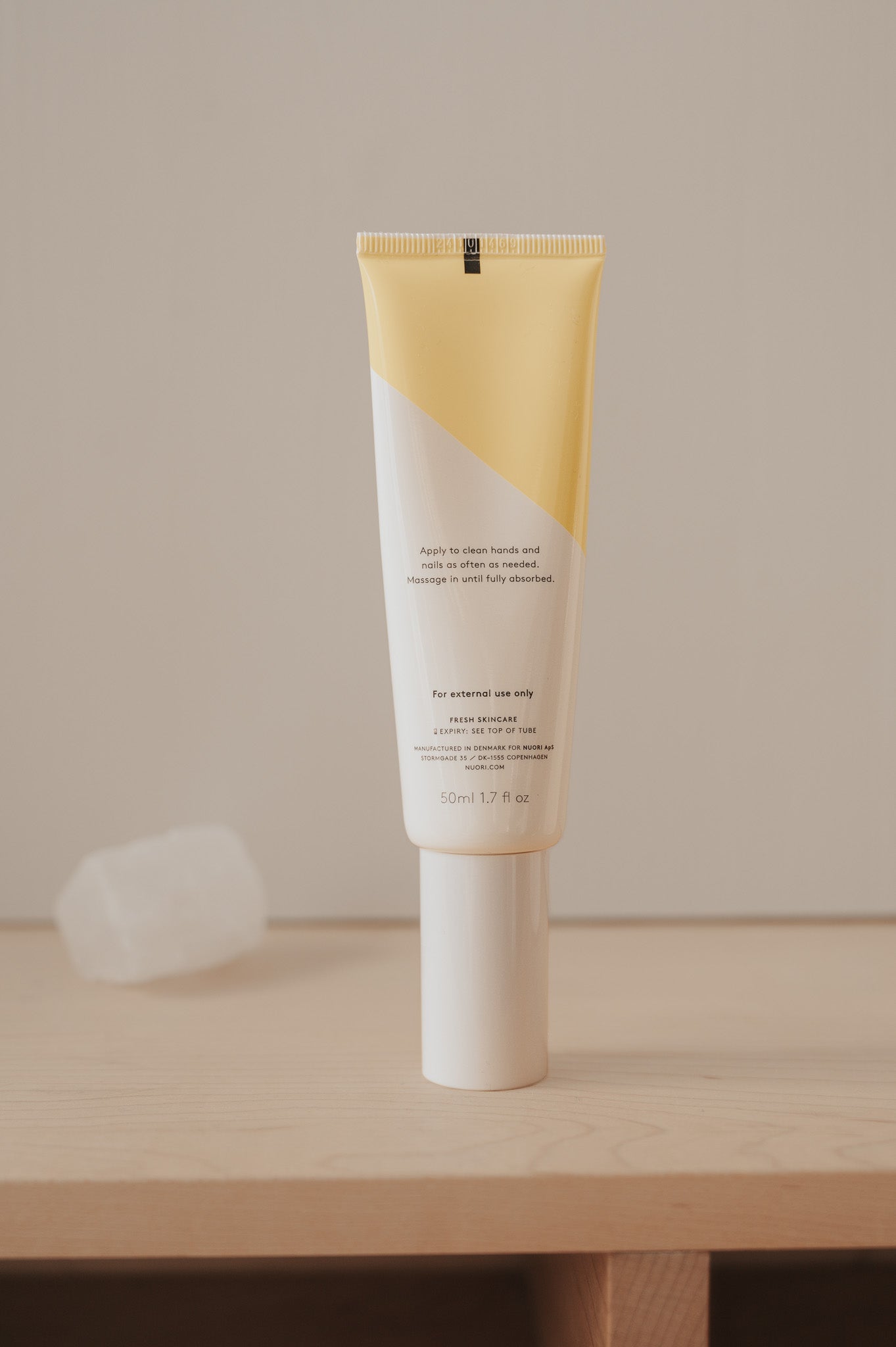 Käsivoide NUORI VITAL HAND CREAM PURELA 50 ml, valkoinen tuubipakkaus ja kädet levittämässä voidetta.
